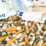 Cigarette butts with euro banknotes background – Concept of wast